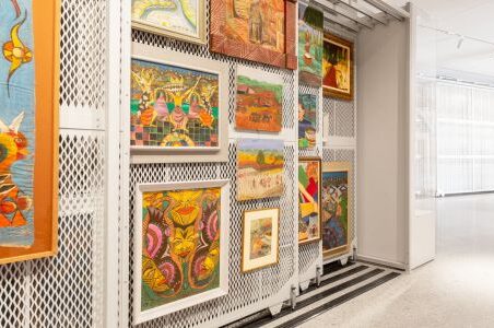 A room filled with an assortment of paintings displayed on art racks, creating a visually captivating atmosphere.