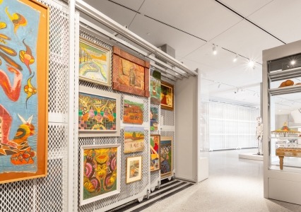Inside a museum, arts racks showcase a variety of paintings on display for visitors.