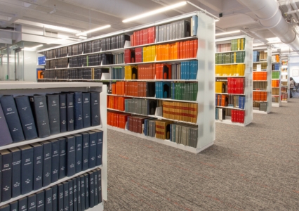 A library featuring illuminated cantilever shelving filled with a variety of books on display.
