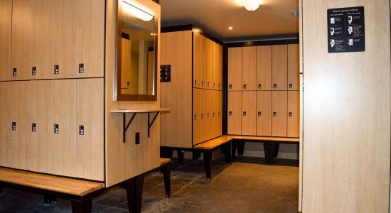 A spacious locker room in a spa, filled with numerous day use lockers and benches.