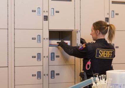 A woman in uniform opens a Spacesaver evidence locker.