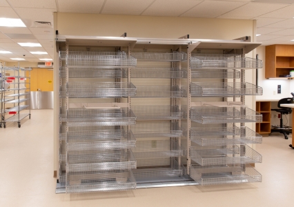 A beige-walled room features a FrameWRX® shelving unit with multiple shelves and wire baskets.