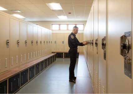 Man in uniform opens a Spacesaver freestyle locker in a locker room.