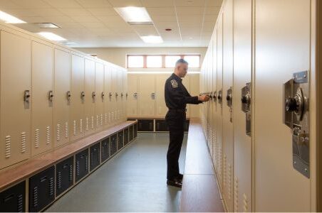 Man in uniform opens a Spacesaver freestyle locker in a locker room.