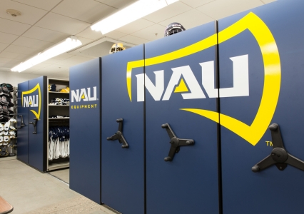 Locker room with mechanical assist mobile system featuring blue and yellow logo, neatly storing sports gear and jerseys.
