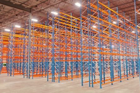 A spacious warehouse showcasing vibrant orange and blue racks featuring a selective racking system.