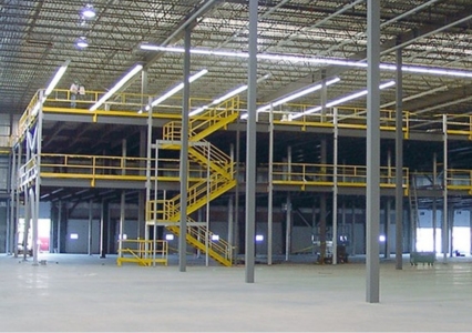 Multi-level structural mezzanine with a yellow staircase and railings in a large warehouse.