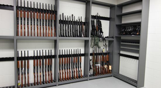 Numerous guns neatly arranged on a weapon rack within a room.