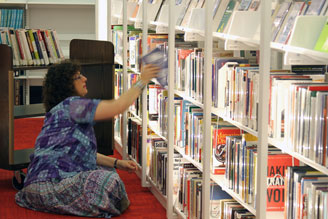 A Librarian putting books back onto a Cantilever Library space saver shelf