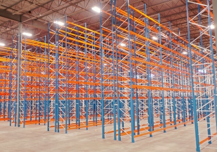 A well-lit warehouse featuring an empty orange and blue selective racking system.