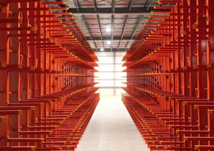 A spacious warehouse featuring red cantilever racking on both sides.