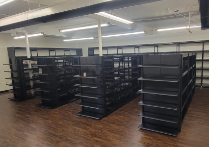 A library featuring light wood library cantilever shelving filled with books and several computers for public use.