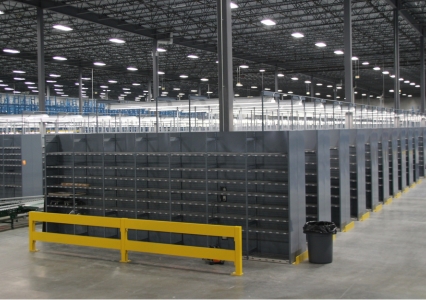 A large warehouse showcases rows of tall, dark gray E-Z-Rect Type 1 shelving units under a high ceiling.