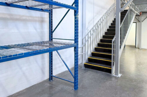 Hi-Cube-Storage-Aerospace-Case-Study-Langley-BC-3 A section of a blue selective pallet racking near a staircase