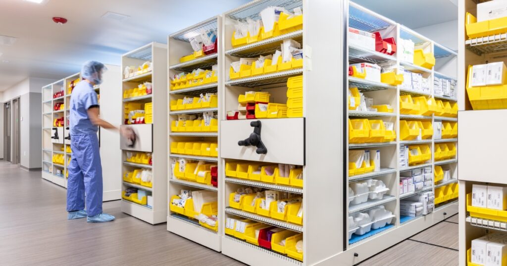 Healthcare worker in scrubs accessing supplies organized in a high-density mobile storage system