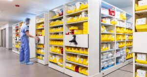 Healthcare worker in scrubs accessing supplies organized in a high-density mobile storage system