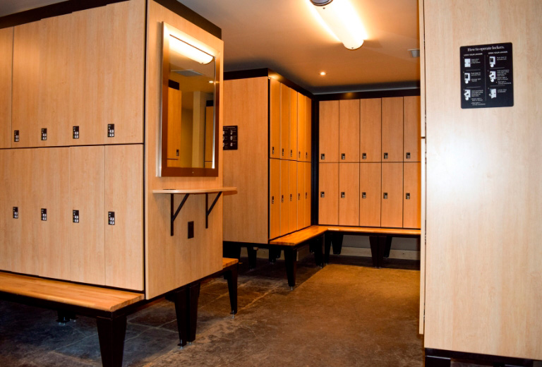 Large wellness locker room showcasing light wood day use lockers and benches for guests’ convenience.