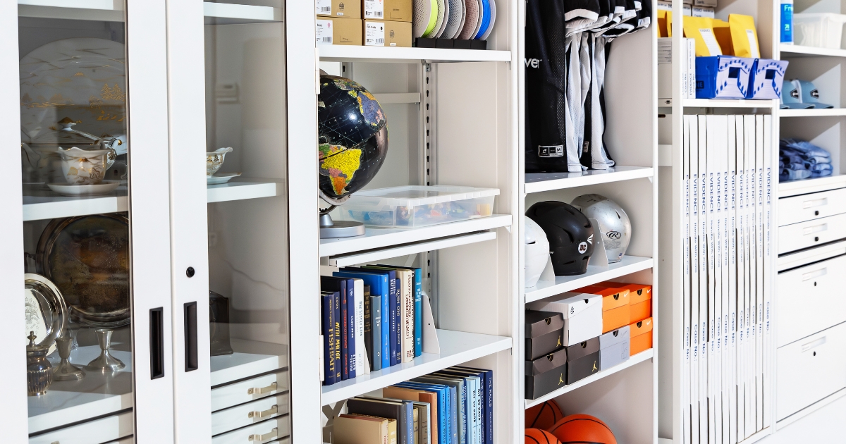 A white, multi-section 4-Post FreeSpan™ Shelving system showcases a mix of closed glass-front cabinets, open storage for books and sports gear, and organized file storage.