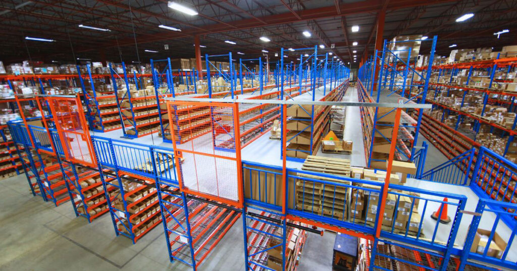 Overhead perspective of a multi-level shelf-supported mezzanine work platform complete with blue safety handrails and orange sliding safety gates.